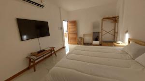 a white bedroom with a large bed and a television at baan Thankhun in Ban Rangeng