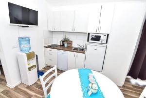 cocina pequeña con armarios blancos y nevera blanca en Apartments with a parking space Vir - 22542, en Vir