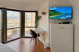 a bedroom with a desk and a tv on a wall at 1BR Ocean Sunset View With Parking in Honolulu