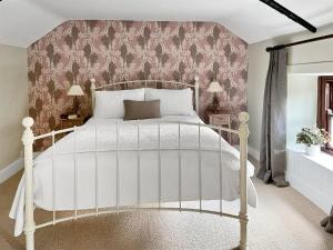 a bedroom with a white bed with a pink wall at Mill View Cottage in West Stour