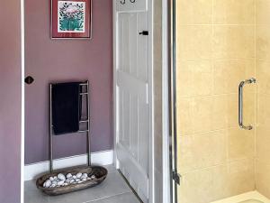 a bathroom with a shower and a basket of rocks at Mill View Cottage in West Stour