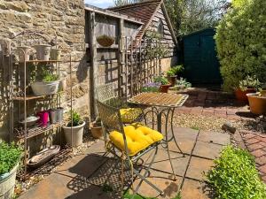 a chair with a yellow cushion sitting in a garden at Mill View Cottage in West Stour