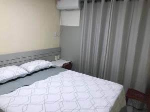 ein Schlafzimmer mit einem weißen Bett und einem Vorhang in der Unterkunft Quarto no Dubai Residence in São Luís