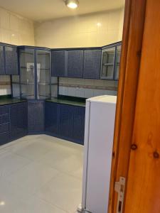 a kitchen with blue cabinets and a white refrigerator at درة الشمس للشقق المفروشة in Ahad Rafidah