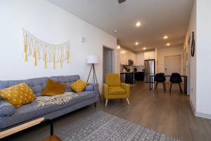 a living room with a blue couch and a yellow chair at Modern Nulu 2BR CozySuites 01 in Louisville