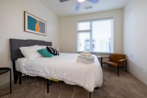 um quarto com uma cama, uma janela e uma cadeira em Modern Nulu 2BR CozySuites 01 em Louisville