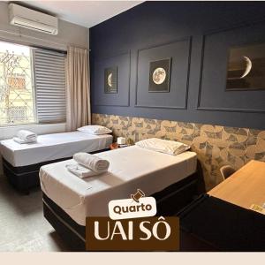 a hotel room with two beds and a sign that reads quora uaila at Kim Casa BH in Belo Horizonte