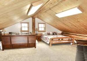 duża sypialnia na poddaszu z łóżkiem i umywalką w obiekcie Log Haven in Blanding w mieście Blanding