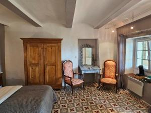 um quarto com uma cama, uma secretária e cadeiras em Chambre Voltaire em Saint-Sauveur-de-Cruzières