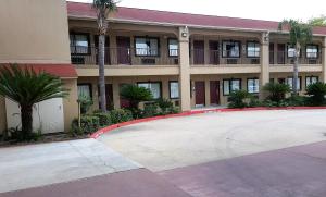 a large building with palm trees in front of it at Red Roof Inn & Suites Houston – Humble/IAH Airport in Humble