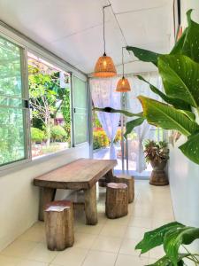 a wooden table and stools in a room with windows at River Flow House Bangtanod in Ratchaburi +16 photos