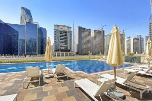 einen Pool mit Stühlen und Sonnenschirmen in einer Stadt in der Unterkunft Silkhaus Business Bay in new Building Large studio with bedroom in Dubai