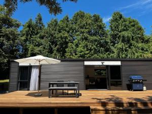 a wooden deck with a bench and an umbrella at Pond Road Park - Raglan in Raglan