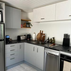 eine Küche mit weißen Schränken und Küchengeräten aus Edelstahl in der Unterkunft Pond Road Park - Raglan in Raglan