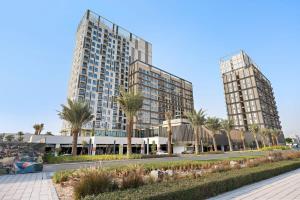 twee hoge gebouwen met palmbomen voor een straat bij Silkhaus quiet neighborhood at Dubai Hills 1BDR in Dubai