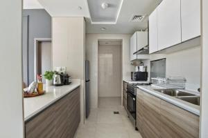 a large kitchen with white cabinets and a sink at Silkhaus Al Reem island Modern 1BDR in Abu Dhabi
