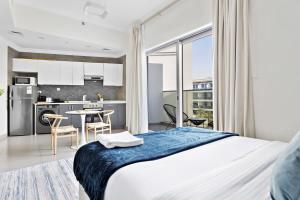a bedroom with a king sized bed and a kitchen at Silkhaus luxurious studio in Art Gardens with gym access in Dubai