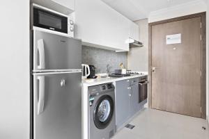 a kitchen with a refrigerator and a washing machine at Silkhaus spacious studio in Art Gardens with gym & pool access in Dubai