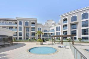 zewnętrzny widok na duży biały budynek z basenem w obiekcie Silkhaus spacious studio in Art Gardens with gym & pool access w Dubaju