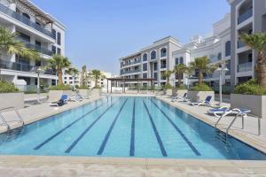 basen z leżakami i budynek w obiekcie Silkhaus spacious studio in Art Gardens with gym & pool access w Dubaju