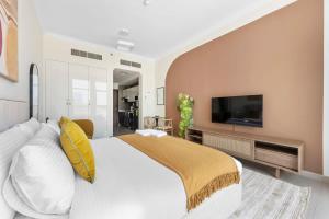a bedroom with a large white bed and a tv at Silkhaus exquisite studio in Art Gardens with gym access in Dubai