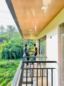 two people standing on the balcony of a house at Greenview in Vythiri