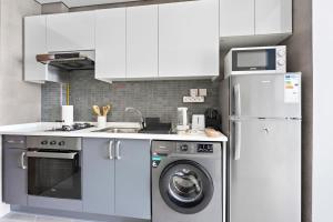 a kitchen with a washing machine and a refrigerator at Silkhaus beautiful studio in Art Gardens with pool access in Dubai