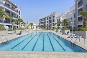 una piscina con sedie a sdraio e un edificio di Silkhaus beautiful studio in Art Gardens with pool access a Dubai