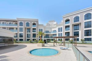 zewnętrzny widok na duży biały budynek z basenem w obiekcie Silkhaus beautiful studio in Art Gardens with pool access w Dubaju