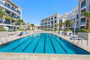 a swimming pool with chairs and a building at Chic Studio in Art Gardens Modern Living in Dubai