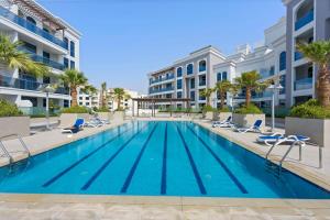 a swimming pool with lounge chairs and a building at Silkhaus new studio in Art Gardens gym & pool access in Dubai