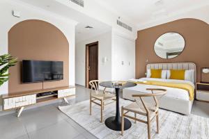 sypialnia z łóżkiem, telewizorem i stołem w obiekcie Silkhaus aesthetic studio in Art Gardens with gym & pool access w Dubaju