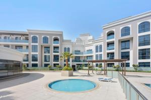 zewnętrzny widok na duży biały budynek z basenem w obiekcie Silkhaus aesthetic studio in Art Gardens with gym & pool access w Dubaju