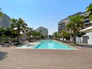 a large swimming pool with palm trees and buildings at Silkhaus Luxury Studio Near Dubai Sport City in Dubai