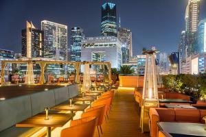a rooftop bar with tables and chairs and a city skyline at Silkhaus chic studio in Sky Gardens Pool & Gym in Dubai