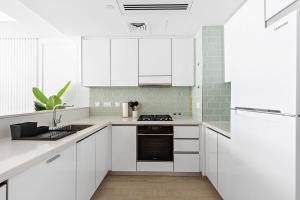 a white kitchen with white cabinets and a stove at Silkhaus Premium Luxury Unit by Aldar with Beach Access in Abu Dhabi