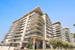 un grand immeuble d'appartements avec des arbres devant lui dans l'établissement Silkhaus Premium Luxury Unit by Aldar with Beach Access, à Abu Dhabi