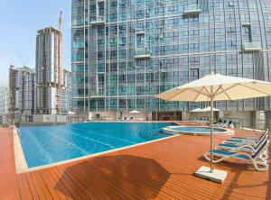 a pool with chairs and an umbrella and a building at Silkhaus Luxurious 1 BDR Al Fay Park Nearby in Abu Dhabi