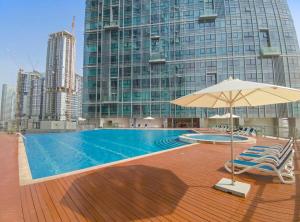 a swimming pool with chairs and an umbrella and a building at Silkhaus Spacious 1 BDR Al Fay Park Nearby in Abu Dhabi
