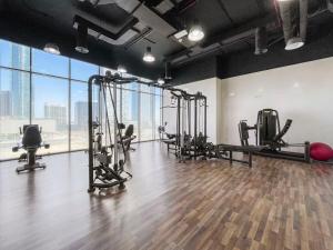a gym with treadmills and machines in a room with windows at Silkhaus High Floor 1 BDR Al Fay Park Nearby in Abu Dhabi
