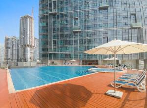een zwembad met stoelen en een parasol op een gebouw bij Silkhaus Modern 1 BDR Al Fay Park Nearby in Abu Dhabi