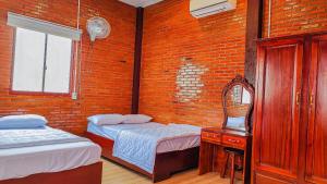 a room with two beds and a mirror in it at HOMESTAY HƯƠNG RỪNG in Tân Phú