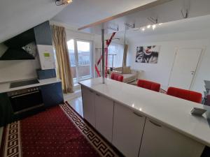 cocina con encimera blanca y sillas rojas en Comfy condo Floresti, en Floreşti