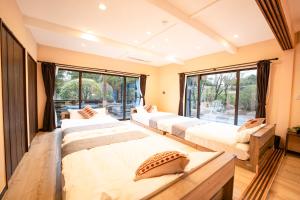 four beds in a room with a large window at 完全貸切別荘 天然温泉 La Saison inn Kirishima 888 in Kirishima