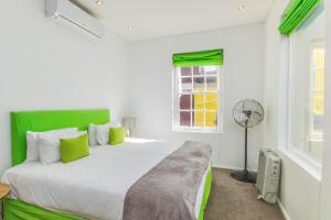 una camera con letto con testiera verde e ventilatore di Luxury 2 Bedroom with roof deck and pool a Città del Capo