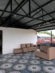 ein Wohnzimmer mit Sofas und einer weißen Wand in der Unterkunft La Veranda Farm Breeze in Batuan