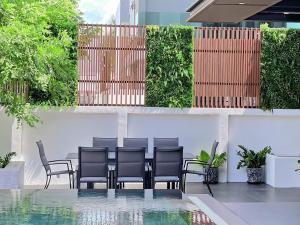 a patio with chairs and a table on a building at Minho Villa Luxury Pattaya in Nong Prue
