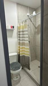 y baño con cortina de ducha y aseo. en Sunset 302, en Antiguo Cuscatlán