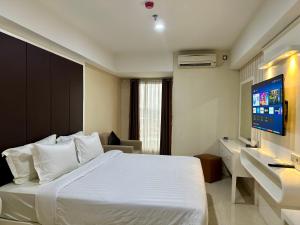 Habitación de hotel con cama blanca y TV de pantalla plana. en KUMU Lantai 18 Warhol Residence at Louis Kienne Simpang Lima Semarang en Semarang