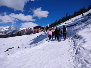 a group of people walking up a snow covered mountain at Moon hotel Tungnath in Chopta